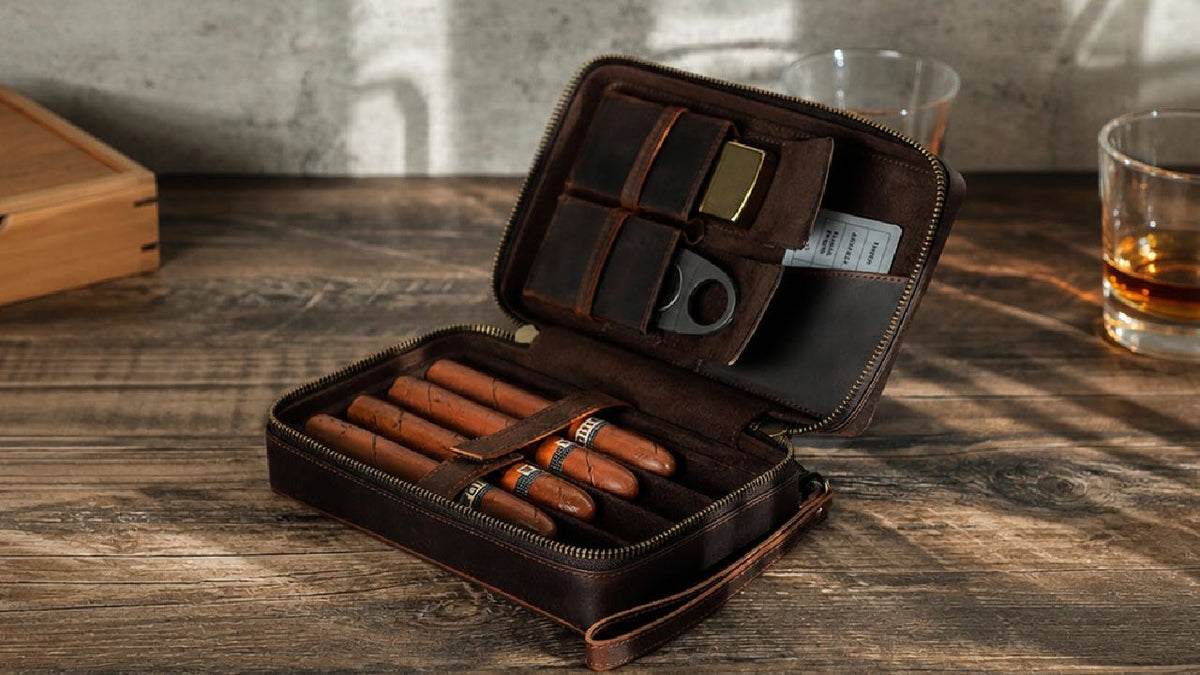 Open brown leather cigar travel case holding cigars, a cutter and lighter