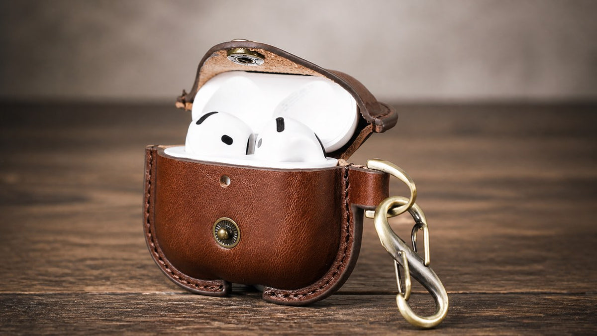 Open brown leather AirPods 4 protective case with snap closure and carrying hook