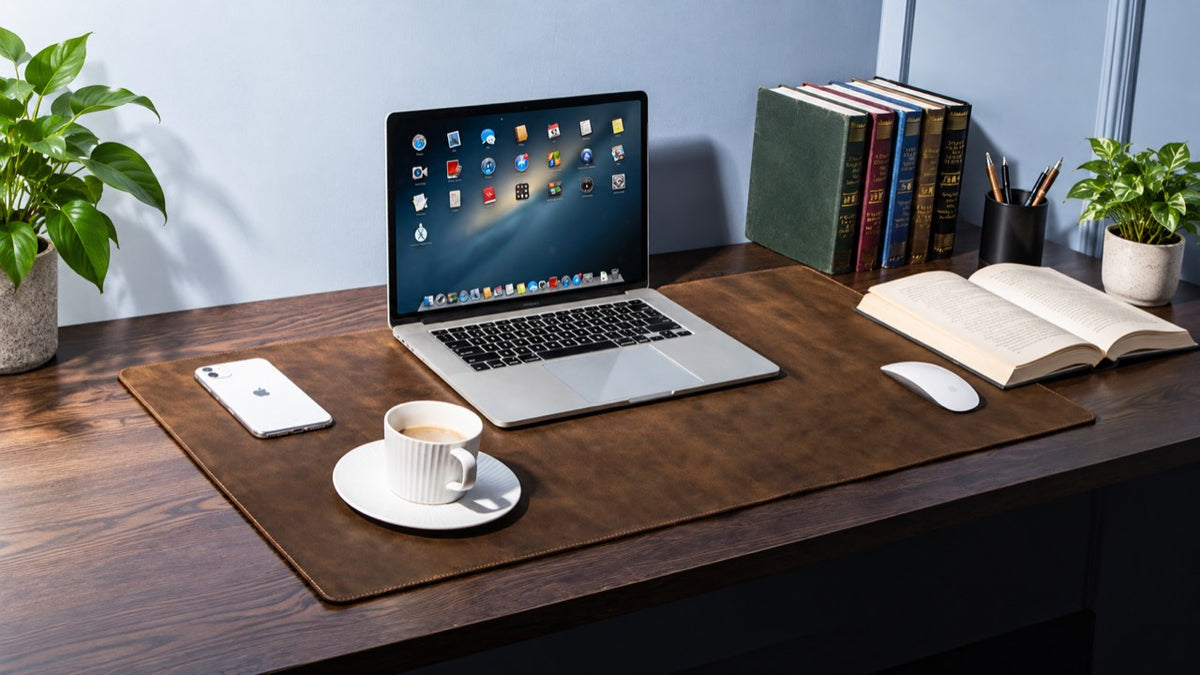 Large brown stitched desk mat beneath a laptop and mouse on a dark wooden desk